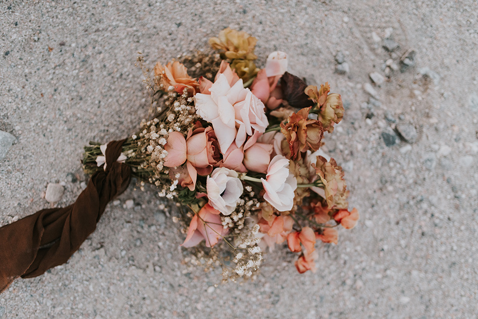  eloping in the desert with a bohemian vibe – bride in a lace gown and the groom in a caramel brown suit – bridal bouquet