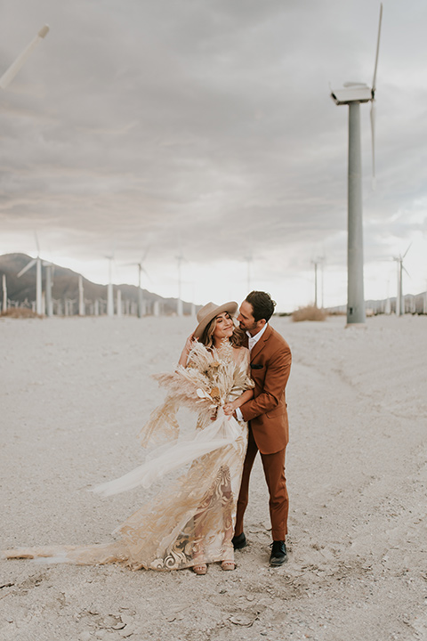  eloping in the desert with a bohemian vibe – bride in a lace gown and the groom in a caramel brown suit -couple embracing