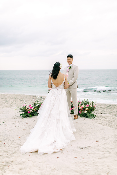  a coastal beach theme with a blush and beige wedding color scheme – bride walking down the aisle 
