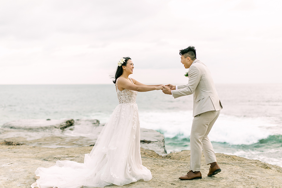  a coastal beach theme with a blush and beige wedding color scheme – couple dancing on the sand