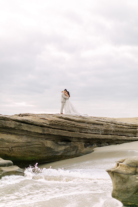  a coastal beach theme with a blush and beige wedding color scheme – couple on the rocks