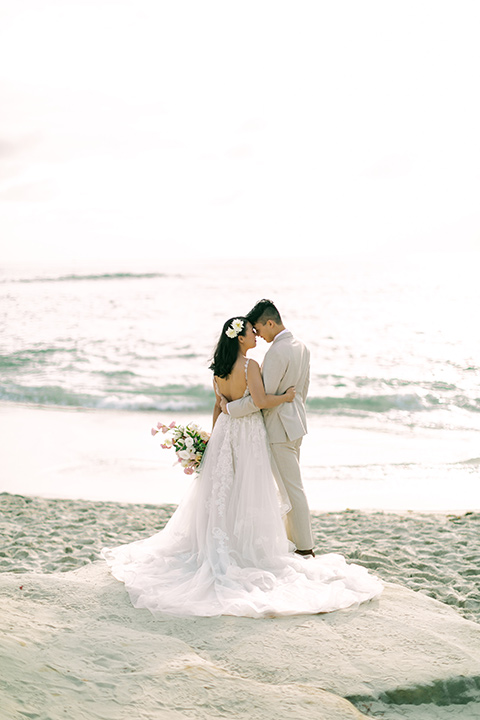  a coastal beach theme with a blush and beige wedding color scheme – couple walking on the sand