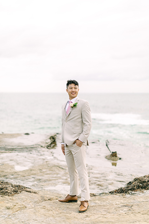  a coastal beach theme with a blush and beige wedding color scheme – groom in his suit