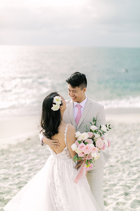  a coastal beach theme with a blush and beige wedding color scheme – couple embracing each other 