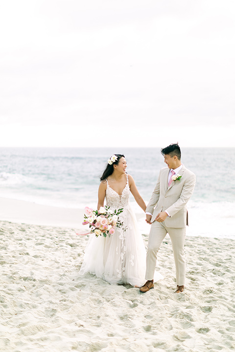  a coastal beach theme with a blush and beige wedding color scheme – couple on the sand 