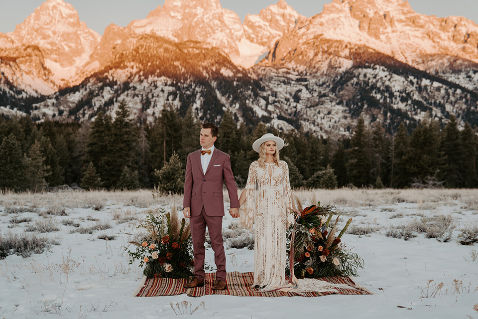  grand tetons elopement in the winter with snow on the ground with the bride in a lace gown and the groom in a rose pink suit – couple at ceremony 