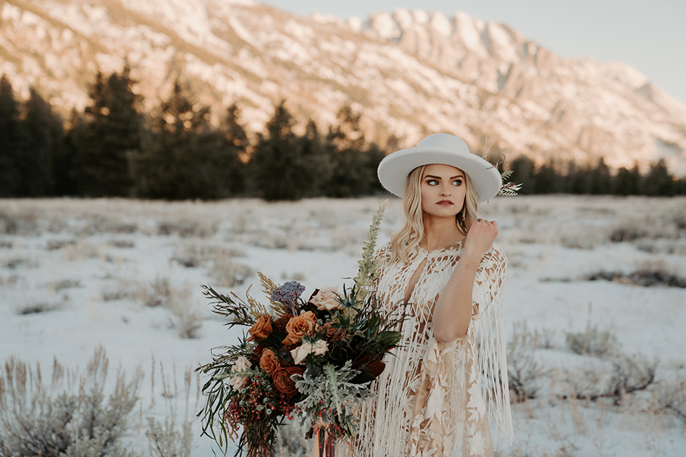  grand tetons elopement in the winter with snow on the ground with the bride in a lace gown and the groom in a rose pink suit – bride with hat 