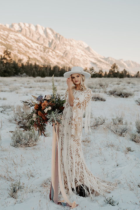  grand tetons elopement in the winter with snow on the ground with the bride in a lace gown and the groom in a rose pink suit – bride in a hat