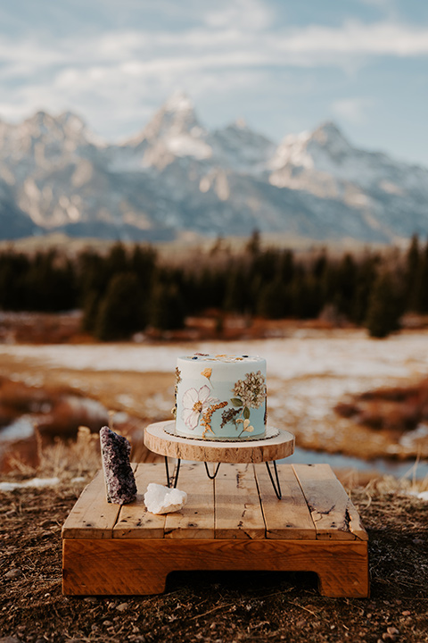  grand tetons elopement in the winter with snow on the ground with the bride in a lace gown and the groom in a rose pink suit – wedding cake 