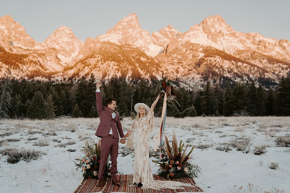  grand tetons elopement in the winter with snow on the ground with the bride in a lace gown and the groom in a rose pink suit – couple at the ceremony 