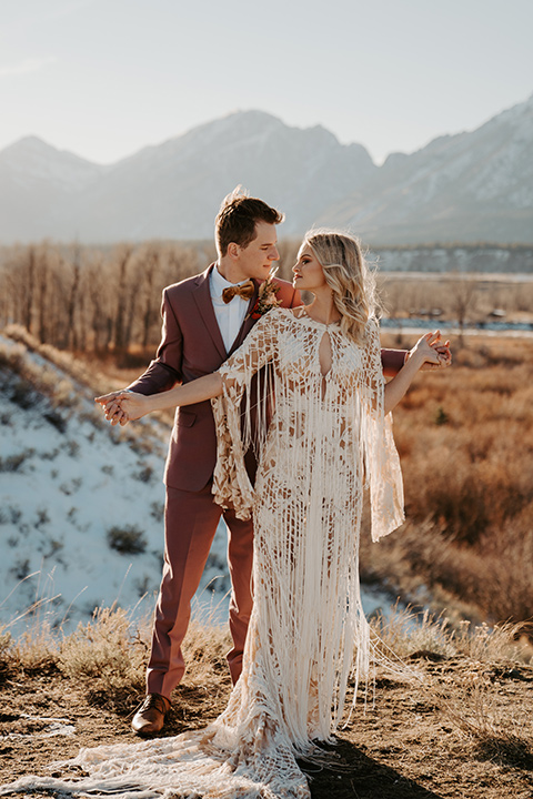  grand tetons elopement in the winter with snow on the ground with the bride in a lace gown and the groom in a rose pink suit – couple dancing in the meadow 