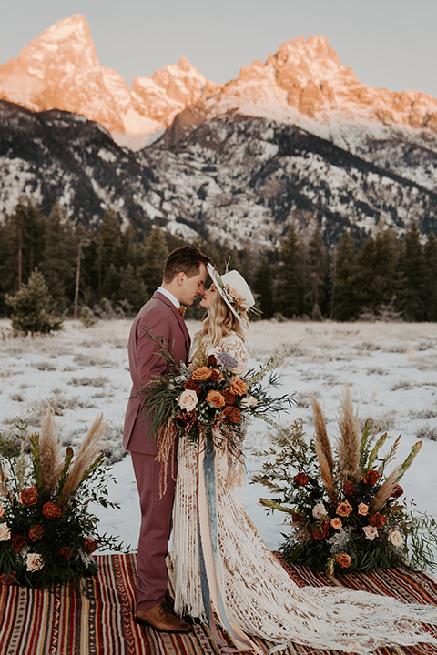  grand tetons elopement in the winter with snow on the ground with the bride in a lace gown and the groom in a rose pink suit – couple at the ceremony