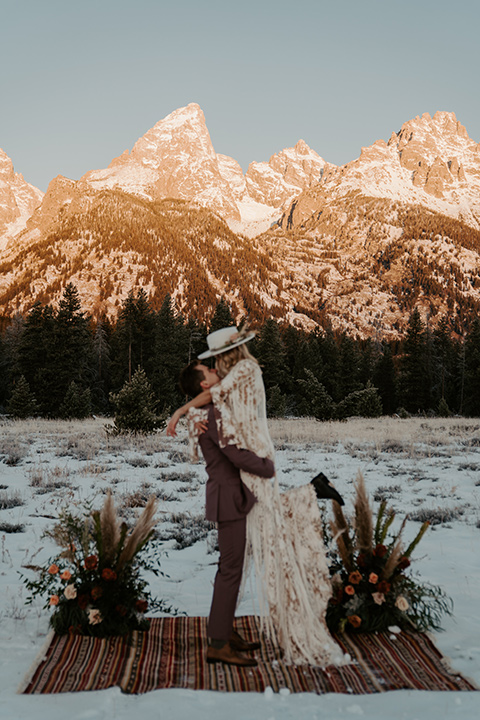  grand tetons elopement in the winter with snow on the ground with the bride in a lace gown and the groom in a rose pink suit – couple at the ceremony 