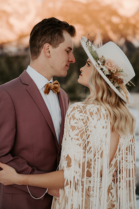  grand tetons elopement in the winter with snow on the ground with the bride in a lace gown and the groom in a rose pink suit – couple kissing 