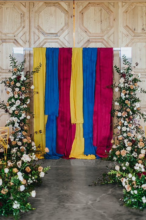  modern and colorful wedding with the bride in an off-the-shoulder dress and the groom in an all-black tuxedo – ceremony space