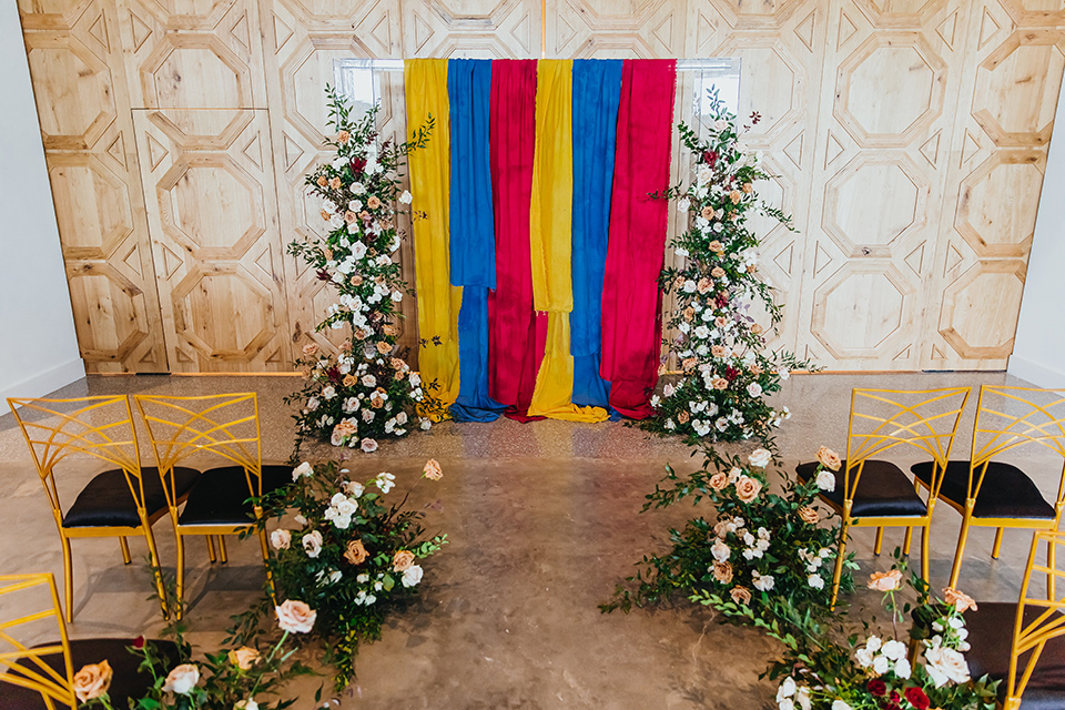  modern and colorful wedding with the bride in an off-the-shoulder dress and the groom in an all-black tuxedo – ceremony space 
