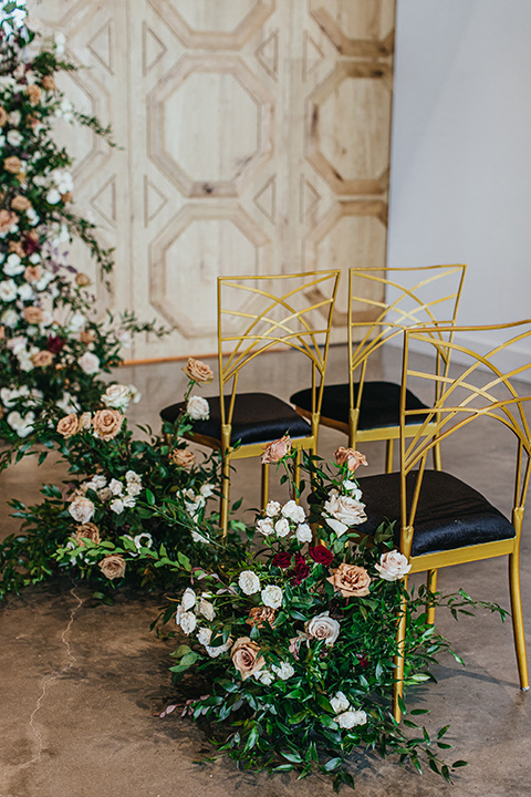  modern and colorful wedding with the bride in an off-the-shoulder dress and the groom in an all-black tuxedo – ceremony gold chairs 