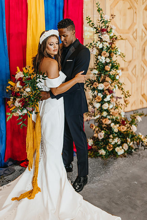  modern and colorful wedding with the bride in an off-the-shoulder dress and the groom in an all-black tuxedo – couple at the ceremony