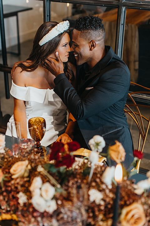  modern and colorful wedding with the bride in an off-the-shoulder dress and the groom in an all-black tuxedo – couple at sweetheart table 