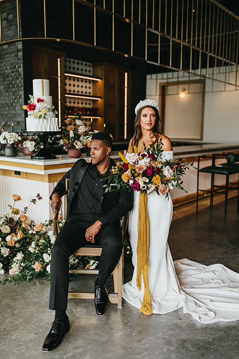  modern and colorful wedding with the bride in an off-the-shoulder dress and the groom in an all-black tuxedo – couple at sweetheart table 