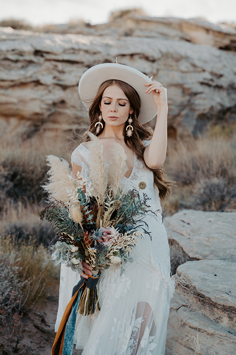  a boho wedding at lake powell with the bride in a bohemian gown and a wide brimmed hat and the groom in a gold velvet jacket – bride in her dress 