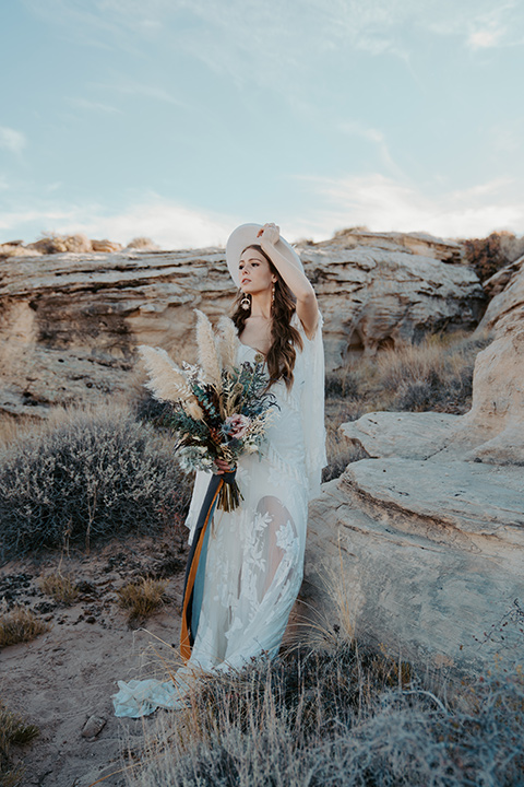  a boho wedding at lake powell with the bride in a bohemian gown and a wide brimmed hat and the groom in a gold velvet jacket – bride in her dress