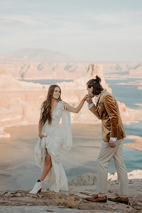  a boho wedding at lake powell with the bride in a bohemian gown and a wide brimmed hat and the groom in a gold velvet jacket – couple at wedding ceremony